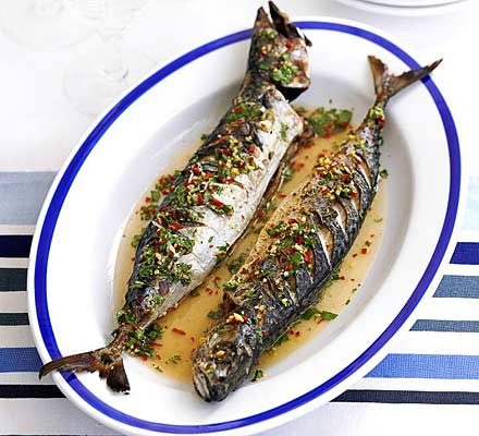 Two pieces of barbecued mackerel on a plate in a lime drizzle