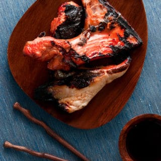 Two cooked Grilled Salmon collars on wooden plate