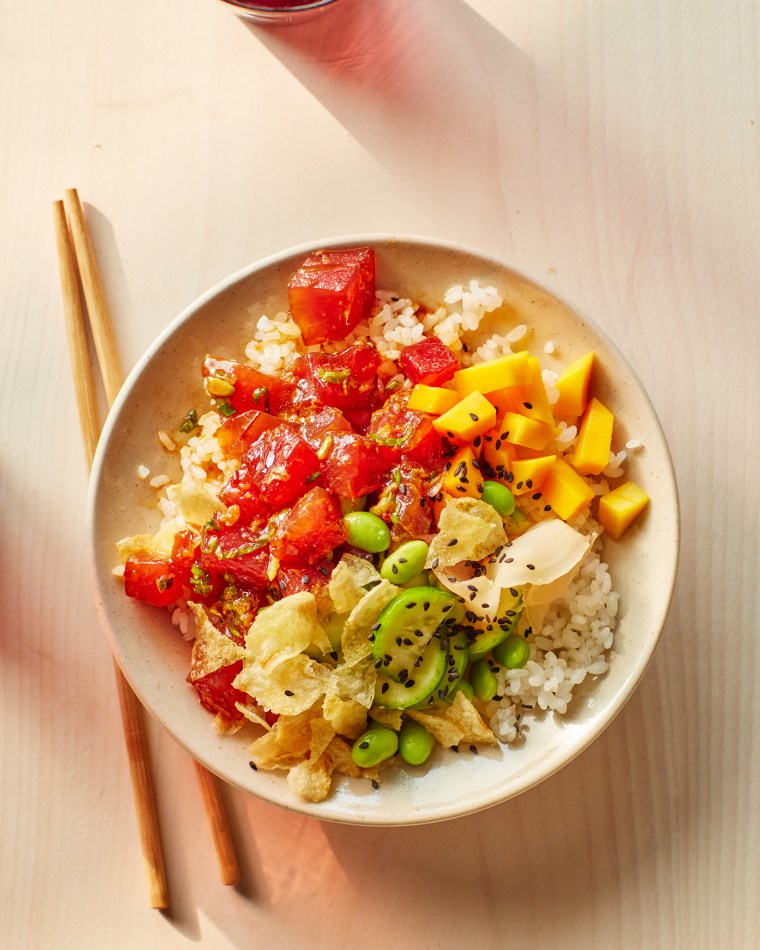 Tuna Poke Bowl on light wooden counter and chopstick laying to the left of bowl