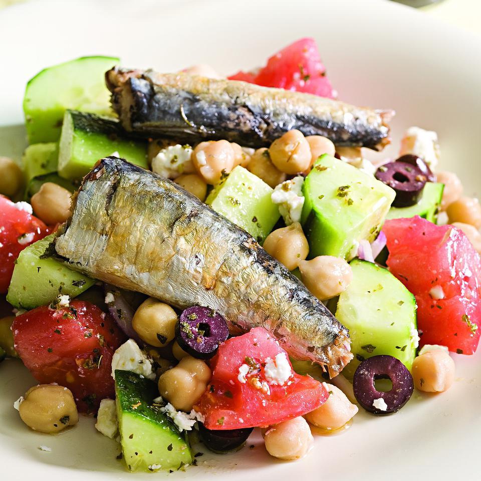 White plate with cooked Sardines, cucumber, tomatoes, and chickpeas