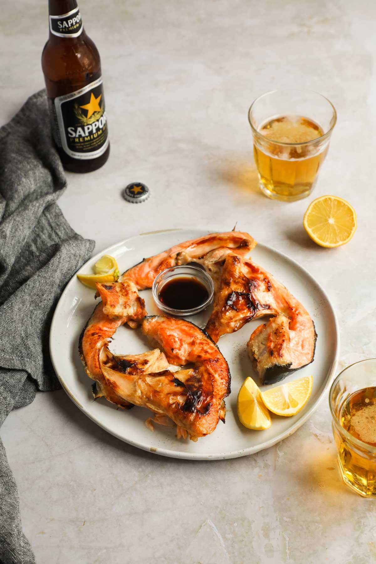 Broiled Salmon Collars (Sake Kama) with Sapporo Beer and lemon.