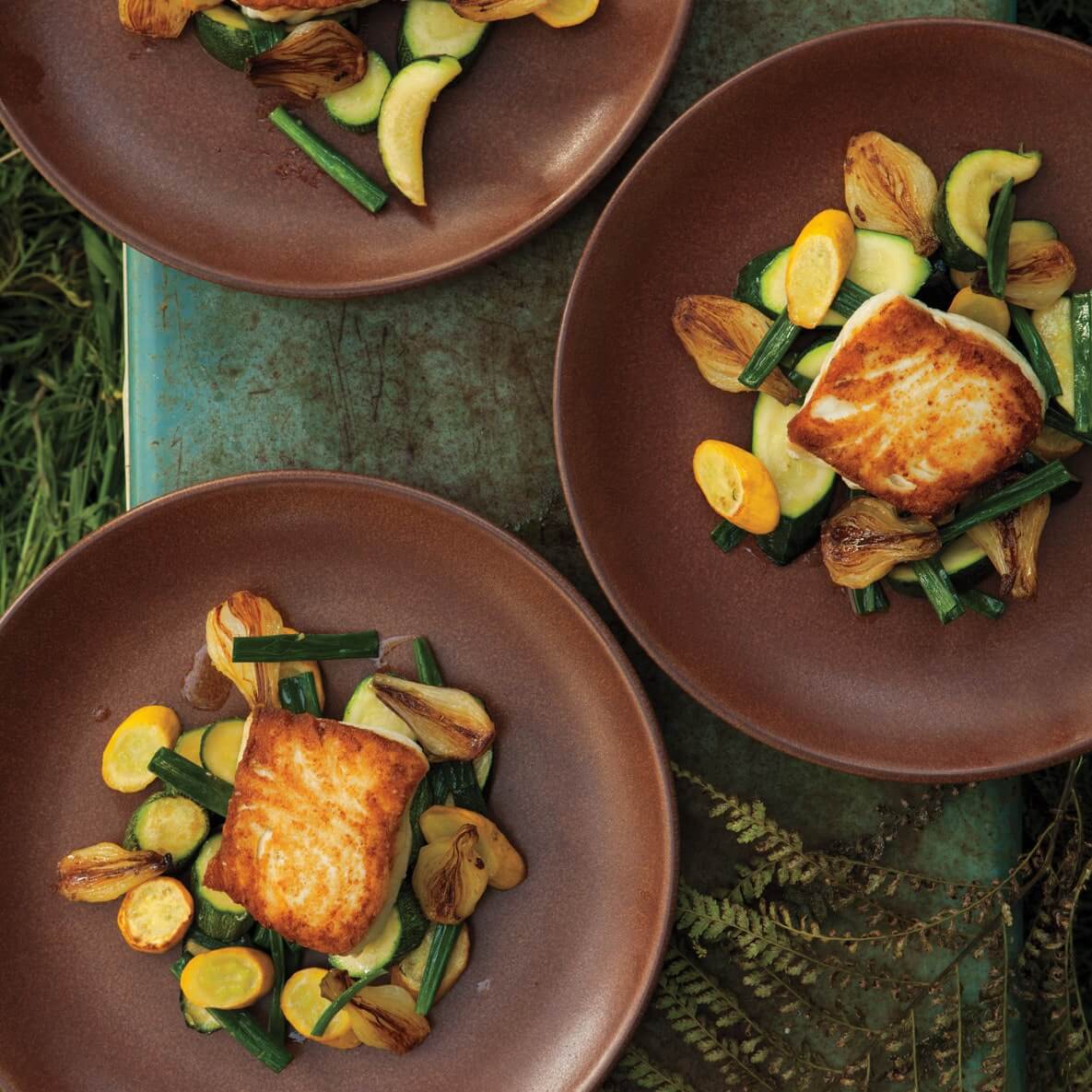 Three brown plates of Halibut with Spring Onion and Summer Squash Saute
