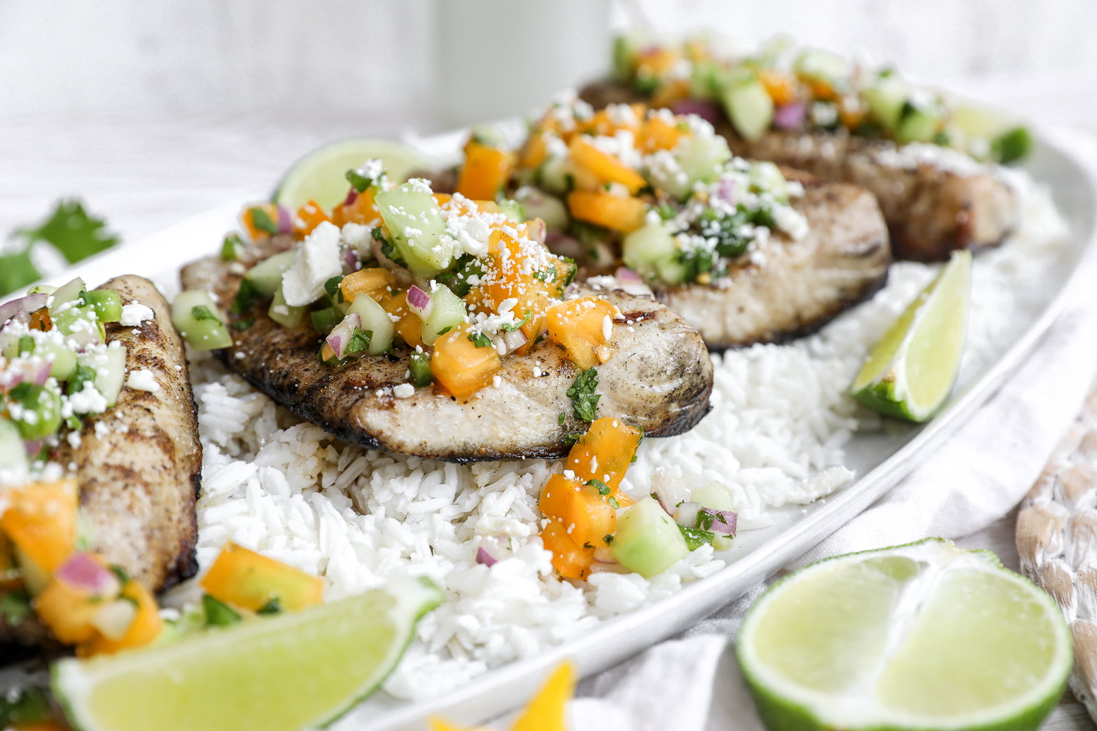 Grilled kanpachi fish with a cucumber jalapeno salsa on a white plate