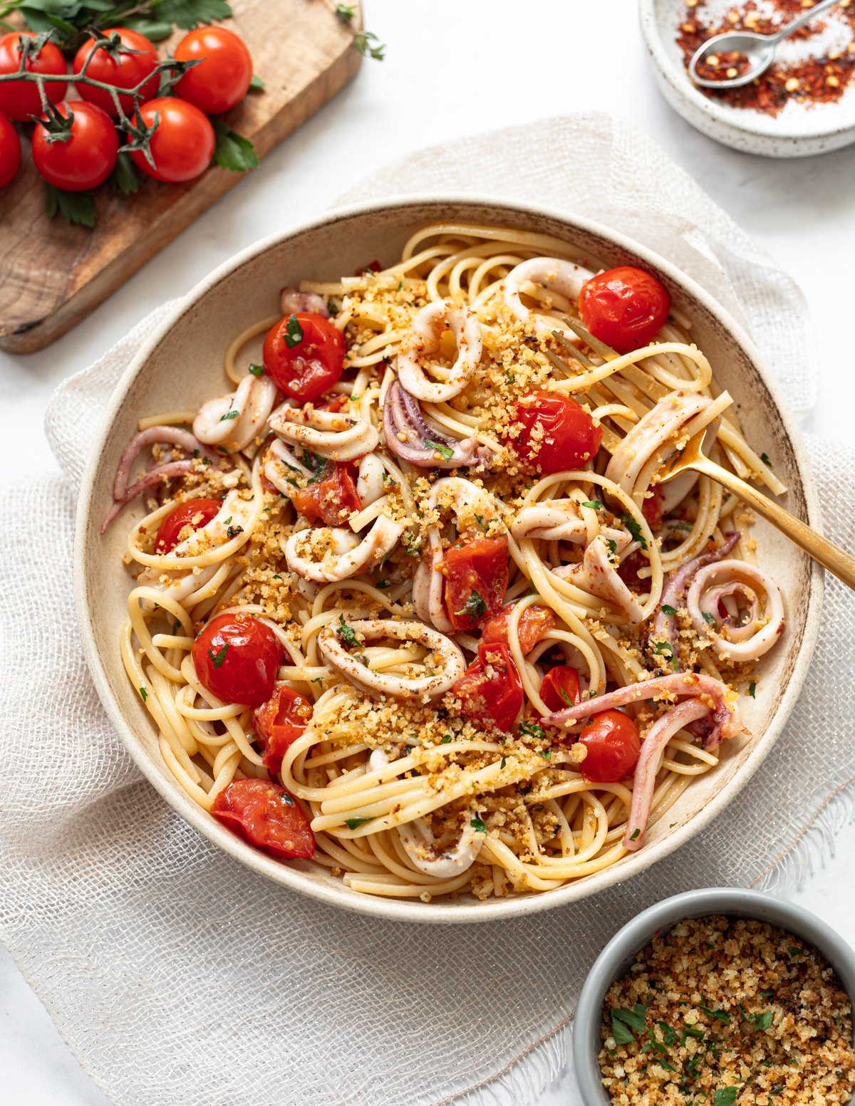 Quick and so tasty! This sheet pan roasted calamari has a garlic and red chili sauce, with cherry tomatoes and breadcrumbs. Serve over spaghetti or your favorite pasta.